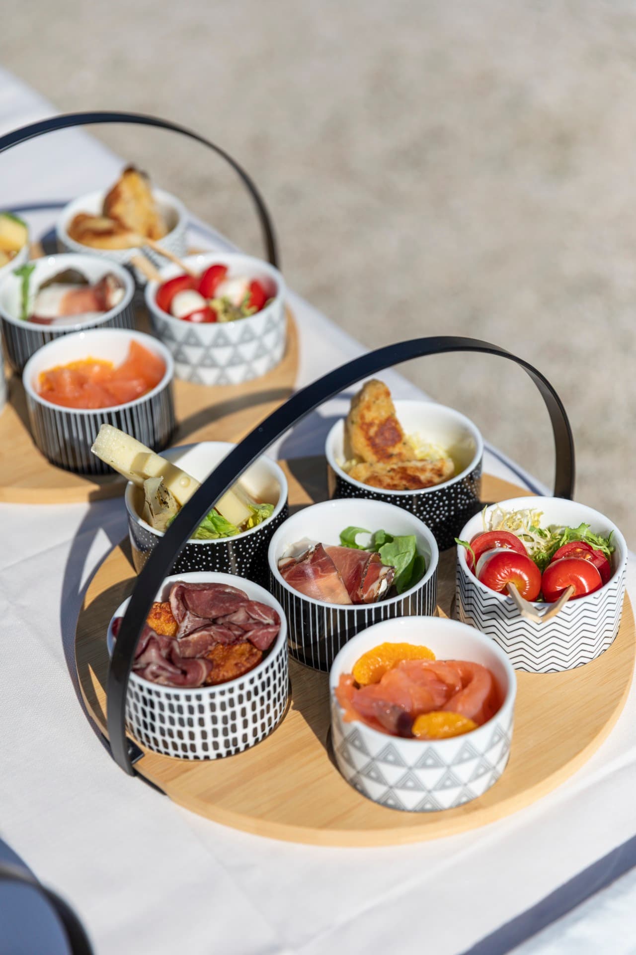Wooden tray of South Tyrolean antipasti in small bowls: speck, cheeses, vegetables and fresh fruit.