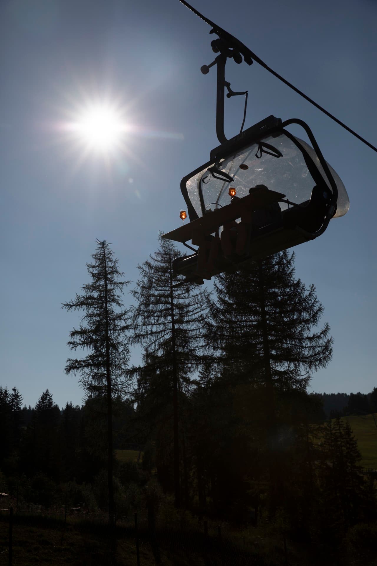 The chairlift silhouetted against the low sun above the larches.